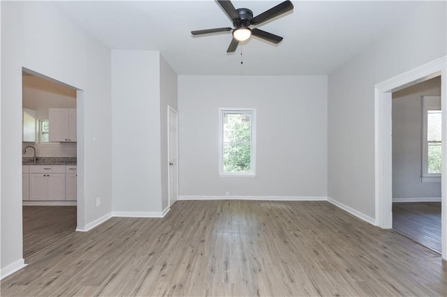 unfurnished room featuring ceiling fan, a healthy amount of sunlight, sink, and light hardwood / wood-style floors