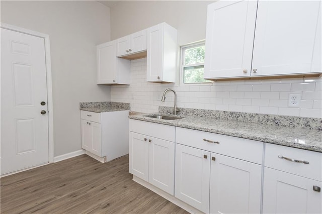 kitchen with sink, hardwood / wood-style floors, tasteful backsplash, light stone countertops, and white cabinets