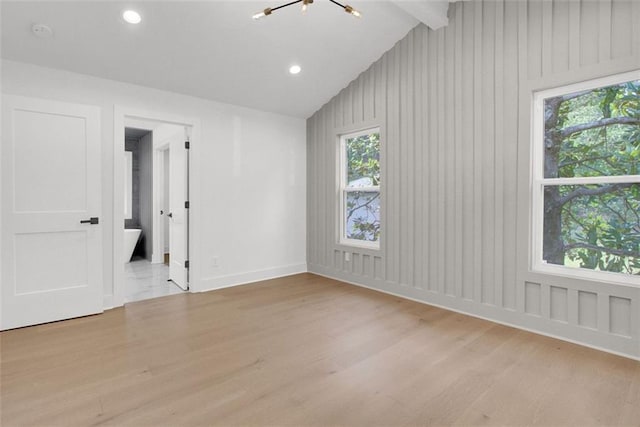 unfurnished room featuring lofted ceiling with beams and light hardwood / wood-style floors