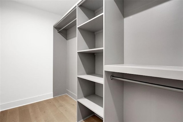 walk in closet with light hardwood / wood-style flooring