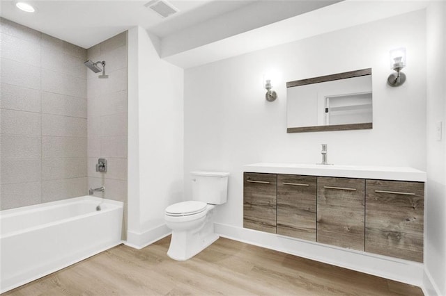 full bathroom featuring tiled shower / bath, wood-type flooring, toilet, and vanity