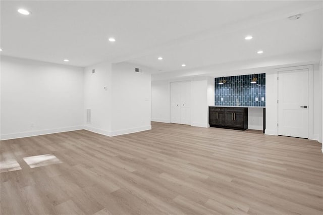 unfurnished living room with bar area and light wood-type flooring