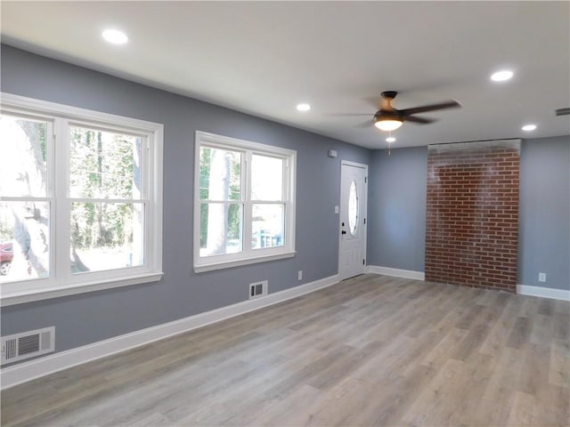 unfurnished room with light wood-style floors, visible vents, and baseboards