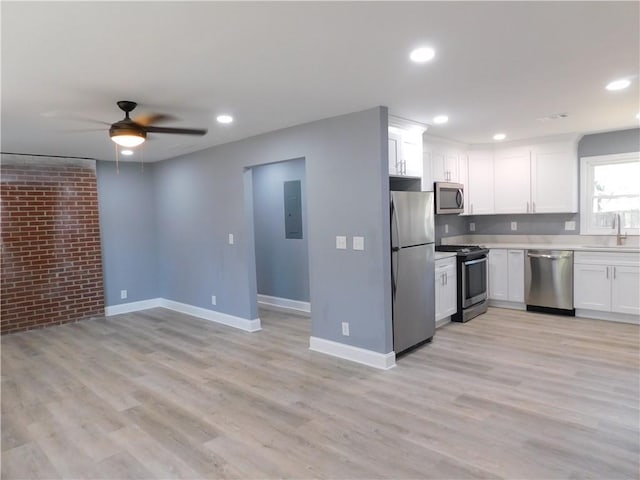 kitchen featuring stainless steel appliances, a sink, white cabinets, light countertops, and electric panel