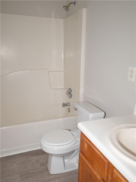 bathroom with toilet, washtub / shower combination, wood finished floors, and vanity