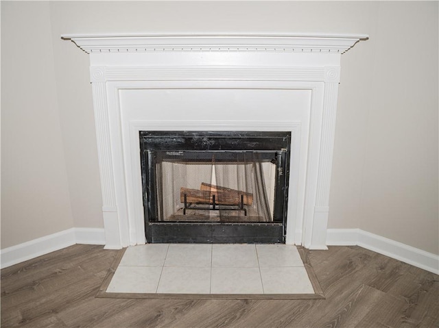 details with a fireplace with flush hearth, baseboards, and wood finished floors