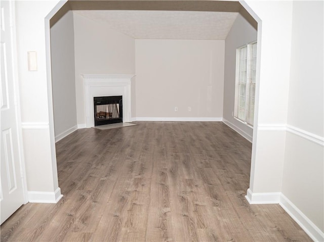 unfurnished living room with a fireplace with flush hearth, light wood-style floors, and baseboards