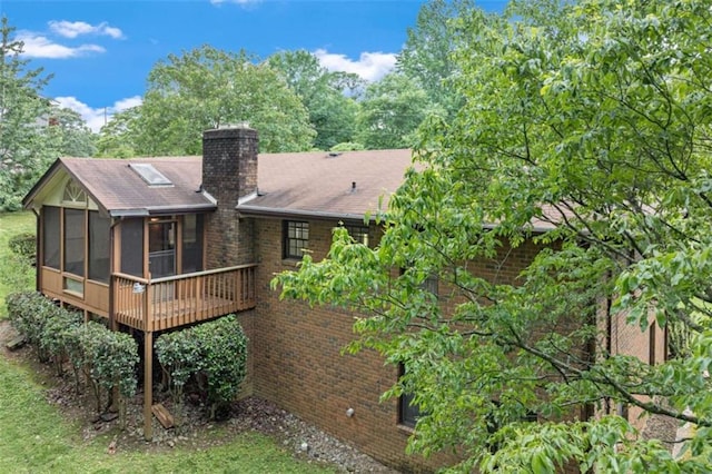 3740 Windy Hill Cir, Gainesville, GA 30504 - back of house featuring a sunroom, a chimney, brick siding, a wooden deck, and a shingled roof