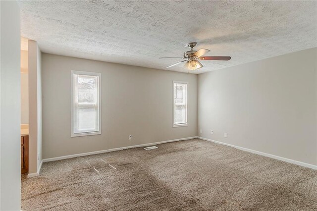 empty room with baseboards, carpet floors, ceiling fan, and a textured ceiling