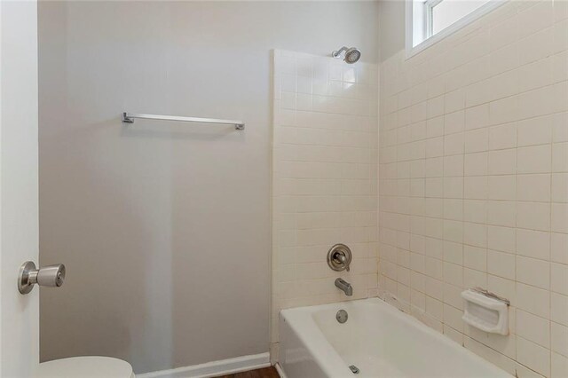 bathroom with toilet, shower / bathtub combination, and baseboards