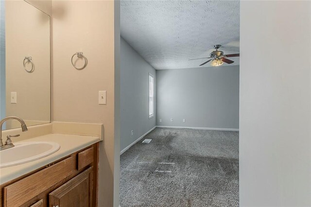 bathroom featuring baseboards, vanity, a textured ceiling, and a ceiling fan