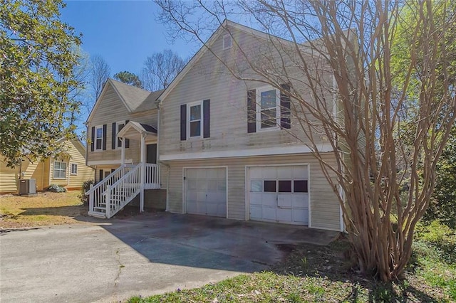 bi-level home featuring driveway, an attached garage, and central air condition unit
