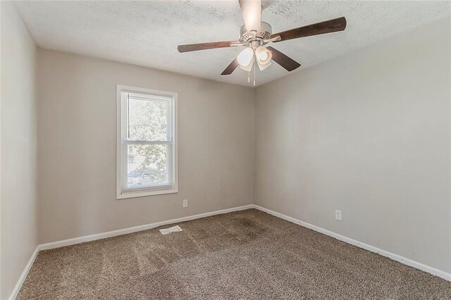 carpeted spare room featuring a textured ceiling, ceiling fan, and baseboards