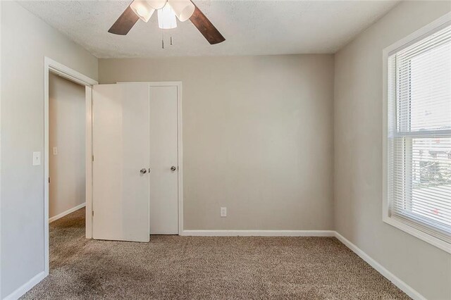 unfurnished bedroom featuring a ceiling fan, carpet, baseboards, and a textured ceiling