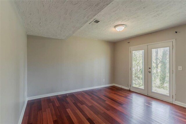 empty room with plenty of natural light, hardwood / wood-style flooring, and visible vents