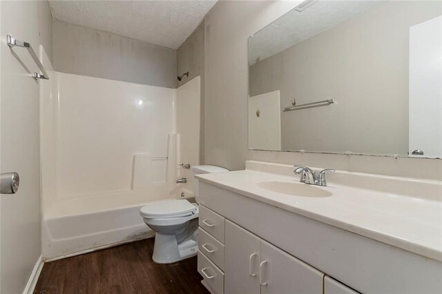 full bathroom featuring a textured ceiling, toilet, wood finished floors, vanity, and shower / bathing tub combination