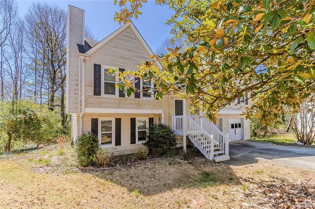 view of front of property featuring driveway, a chimney, and a garage