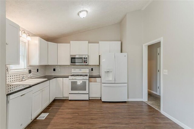 kitchen featuring visible vents, white appliances, lofted ceiling, white cabinetry, and a sink