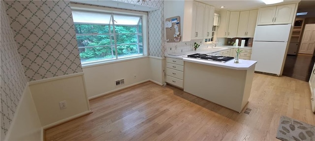 2600 Amberly Dr, Dunwoody, GA 30360 - kitchen featuring freestanding refrigerator, stainless steel gas stovetop, a peninsula, light wood-style floors, and light countertops