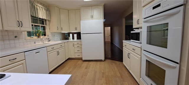 2600 Amberly Dr, Dunwoody, GA 30360 - kitchen with white appliances, light wood-style flooring, decorative backsplash, light countertops, and a sink