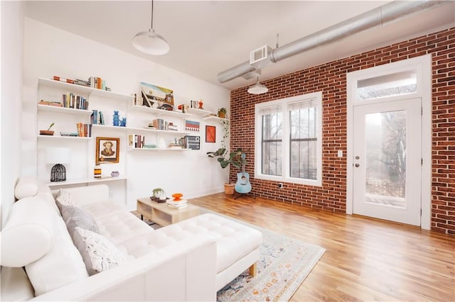 living room featuring light hardwood / wood-style floors and brick wall