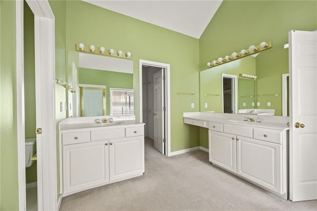 bathroom featuring a sink, baseboards, vaulted ceiling, and two vanities