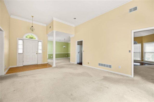 foyer with crown molding, a wealth of natural light, carpet flooring, and visible vents