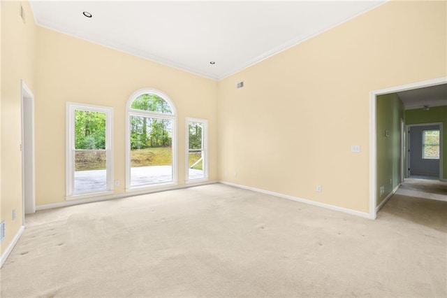 empty room featuring baseboards, plenty of natural light, and light colored carpet