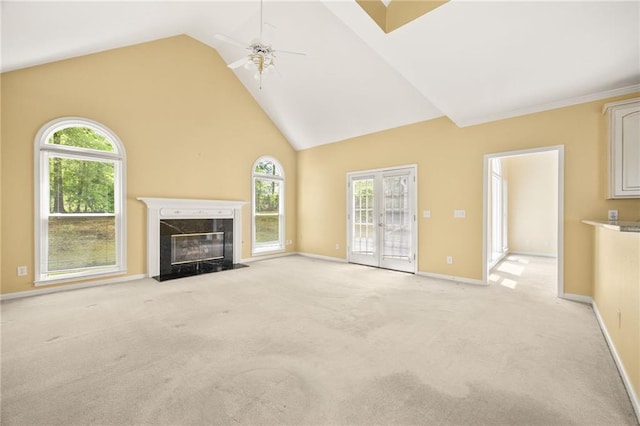 unfurnished living room featuring baseboards, high vaulted ceiling, light colored carpet, a high end fireplace, and a ceiling fan
