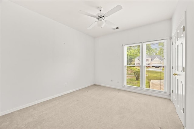 empty room featuring visible vents, a ceiling fan, baseboards, and light carpet