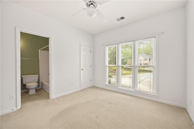 unfurnished bedroom featuring connected bathroom, baseboards, visible vents, and light carpet