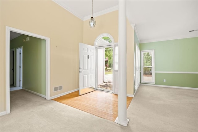 entrance foyer featuring crown molding, carpet flooring, baseboards, ornate columns, and visible vents