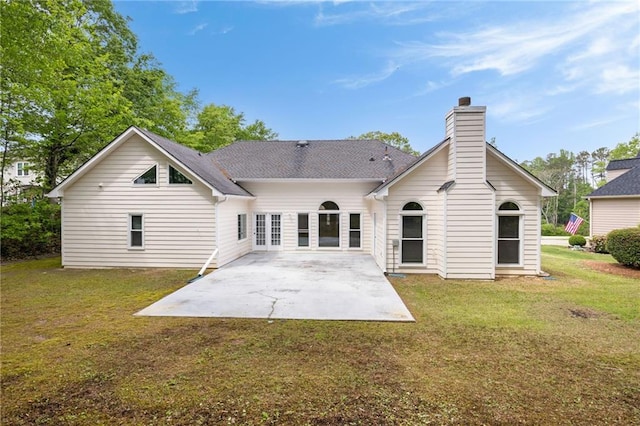 rear view of house with a patio area, a yard, and a chimney