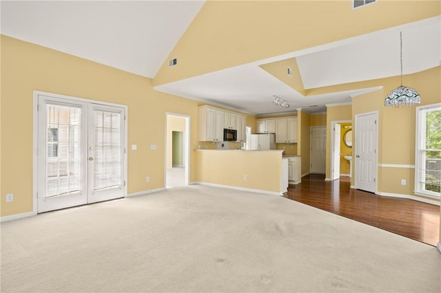unfurnished living room with baseboards, high vaulted ceiling, a chandelier, french doors, and carpet flooring
