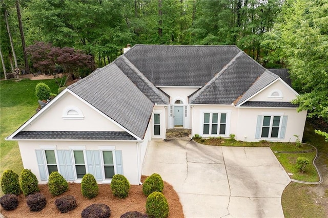 view of front of house featuring a chimney, a front lawn, roof with shingles, and stucco siding
