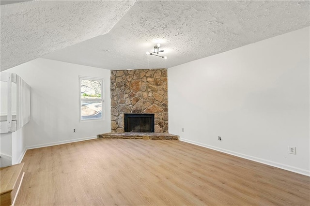 unfurnished living room featuring a textured ceiling, light wood finished floors, a fireplace, and baseboards