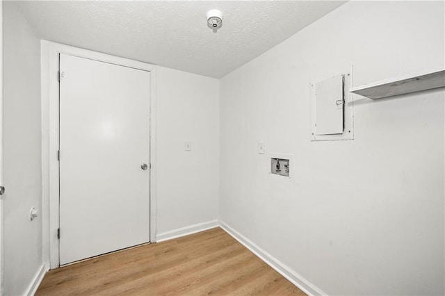 washroom with a textured ceiling, hookup for a washing machine, laundry area, light wood-type flooring, and electric panel