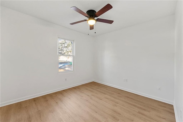 spare room featuring light wood finished floors, baseboards, and a ceiling fan