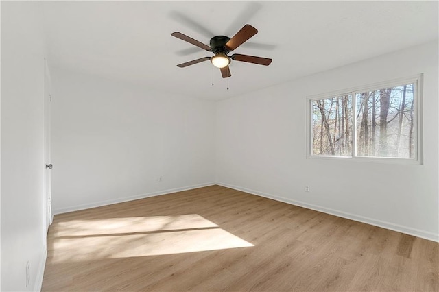 spare room with a ceiling fan, light wood-style flooring, and baseboards