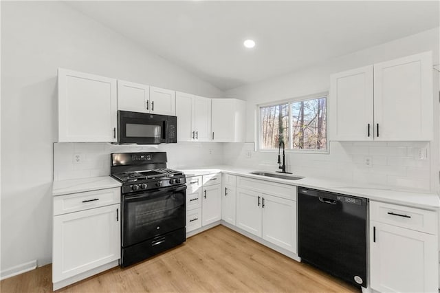 kitchen with black appliances, a sink, and white cabinets