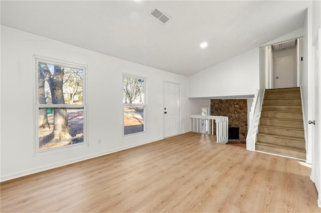 unfurnished living room featuring light hardwood / wood-style floors, a fireplace, and vaulted ceiling