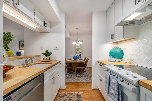 kitchen with butcher block countertops, sink, dishwasher, white cabinets, and decorative light fixtures