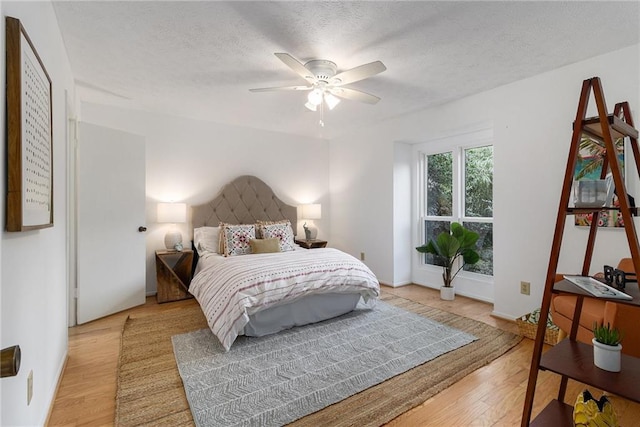 bedroom with ceiling fan, a textured ceiling, and light wood-type flooring