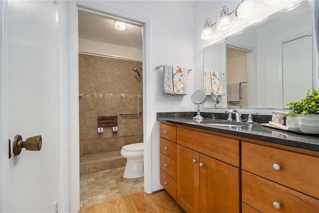 bathroom with vanity, a tile shower, and toilet