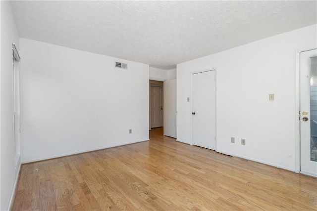 spare room with a textured ceiling and light hardwood / wood-style floors