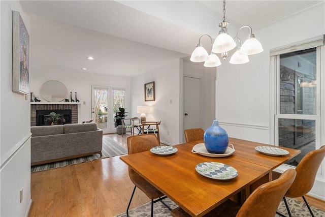 dining area featuring hardwood / wood-style flooring, a brick fireplace, and a notable chandelier