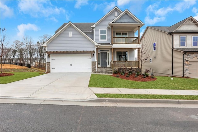 craftsman inspired home featuring a balcony, covered porch, driveway, a front yard, and a garage