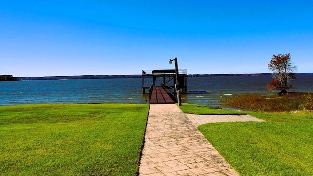 dock with boat lift, a lawn, and a water view