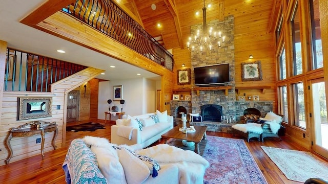 living room with high vaulted ceiling, a stone fireplace, wooden walls, hardwood / wood-style flooring, and a chandelier