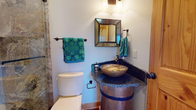 bathroom featuring toilet, a sink, and tiled shower